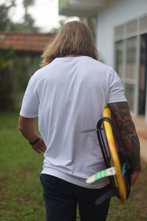 A surfer is depicted riding a red board amidst a vibrant tropical setting, basking in the sun
