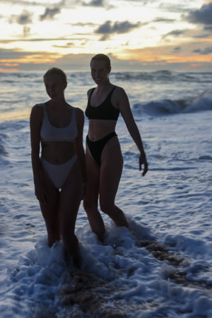 Silhouetted Figures Enjoying a Beautiful Sunset on the Beach with Vibrant Colorsの写真素材