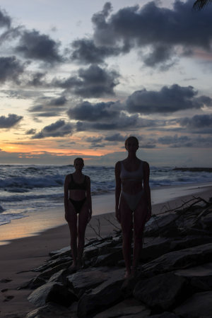 Silhouetted Figures Enjoying a Beautiful Sunset on the Beach with Vibrant Colorsの写真素材