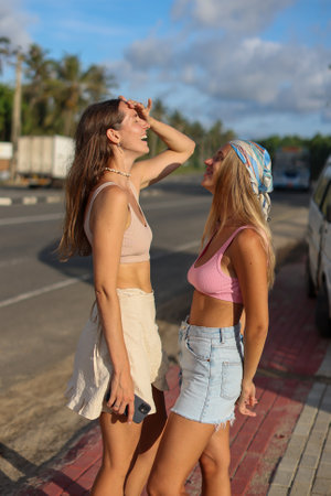 Two women are joyfully posing by the side of the roadの写真素材