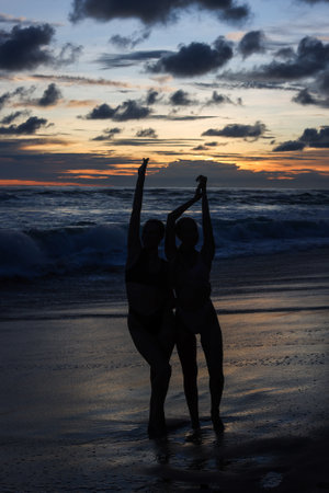 Silhouetted Figures Enjoying a Beautiful Sunset on the Beach with Vibrant Colorsの写真素材