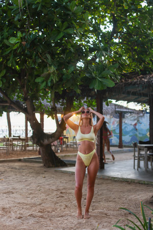 A stunning model in a vibrant yellow bikini poses at the beach, showcasing her cheerful styleの写真素材