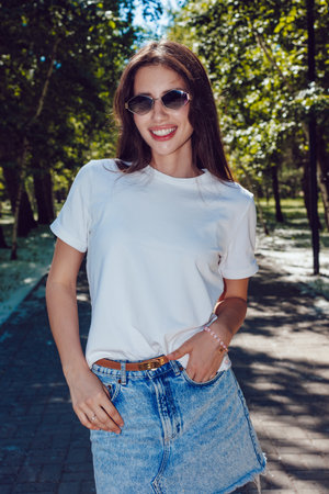 Happy Young Woman In White T-Shirt And Denim Skirt Walking In Parkの写真素材