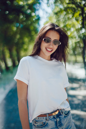 Happy Young Woman In White T-Shirt And Denim Skirt Walking In Parkの写真素材
