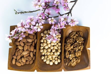 Flat laid healthy raw snack of nuts served in a wooden container, shot from above and isolated on...