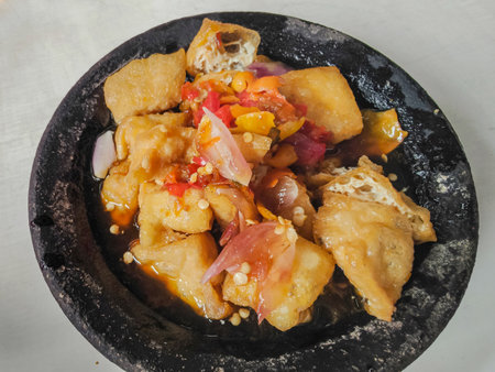Deep fried tofu with chili and sweet and sour sauce on black plate ( tahu gejrot - indonesian dish )の写真素材