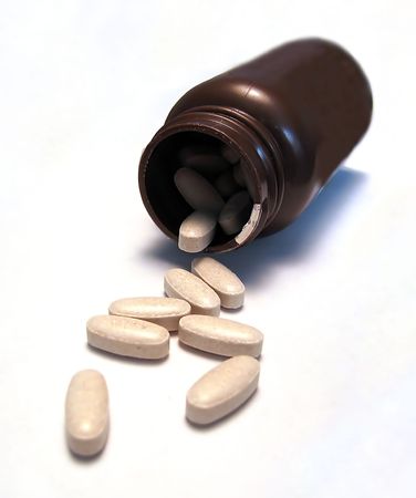 Some generic pills that have fallen out of a brown medicine bottleの写真素材