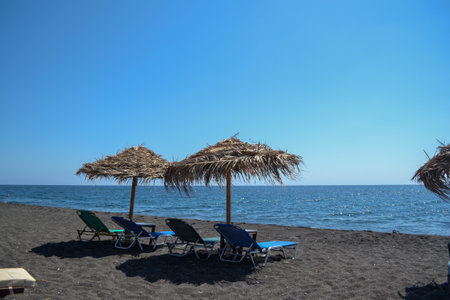 Sun loungers and umbrellas on the black sand beachの写真素材