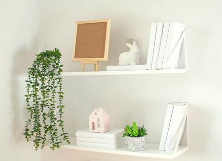 small square mock-up in wooden frame in Scandi-style interior with climbing green plant, bird, books and shelf on an empty neutral-white wall background. Home interior Scandinavian style.の写真素材