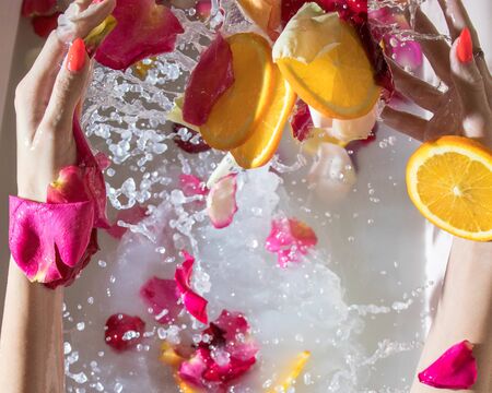 romantic bath with white water oranges girl feet and rose petalsの写真素材