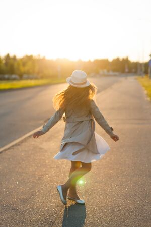 a girl on a Sunny day stands on the road and makes a turn. the concept of happiness.の写真素材