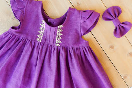 purple linen dress for a girl on a wooden background. children's clothes. fashionable dressの写真素材