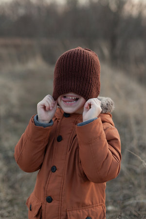 Open autumn portrait of a cute boy dressed in a brown jacket and hat, a child having fun in the Parkの写真素材