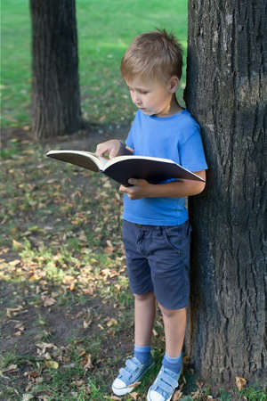 the boy stands up and holds a textbook in his hand and reads.の写真素材