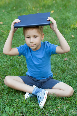 Young boy enjoying his reading book in outdoor parkの写真素材