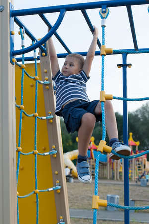 a boy on a childrens Playground in the open air. Rope ladder. Summer day.