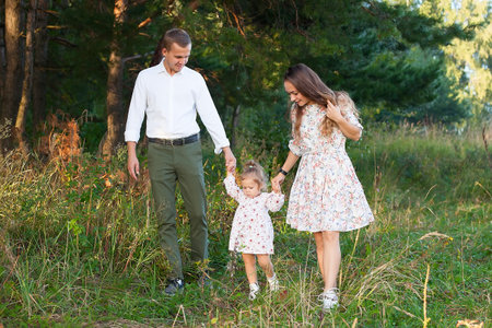 A family of three walks in the woods. Mom, dad, daughter. Family walksの写真素材