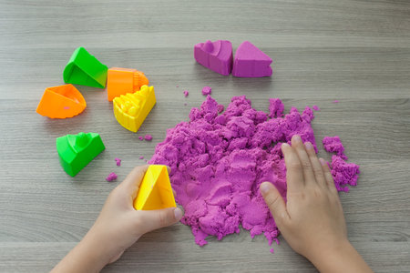 bright pink kinetic sand in the hands of a child. Development and education. Fine motor skills.の写真素材