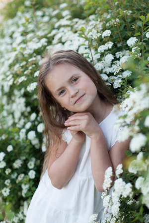 Beautiful preteen girl with long blond hair enjoy spring apple blooming. Little preschool girl in garden tree flowers. Springtime. Copy space. Bannerの写真素材