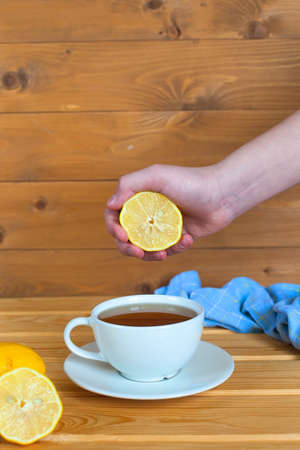 Man's hand squeezing half a lemon into a bowlの写真素材