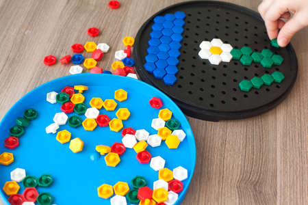 A toddler plays with a plastic mosaic on the carpet in the children's room. Early development.