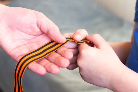 orange and black striped ribbon symbol on May 9 in hands isolated on white background. Victory Dayの写真素材