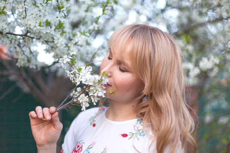woman in a long dress in a spring garden. Tender photo with white flowers