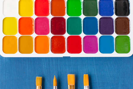 watercolor paints and a brush. an artist's tool. bright colors, school colors.