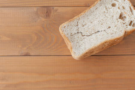 a piece of dry bread on a wooden table. old food. Food for animals.の写真素材