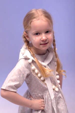 A little beautiful and sweet girl in a stylishly festive dress and with a dwarf hat in a white interior. Photo with selective focus and tinting.The child smiles and looks at the camera.の写真素材