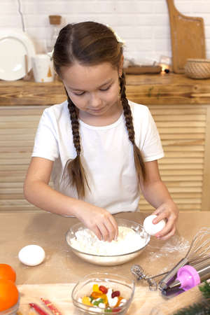 Cute children decorate cookies at the table in the home kitchen, New Year's holidays. Preparation of gingerbreadの写真素材