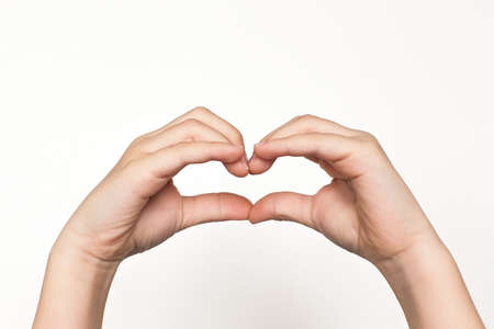 the hands of children's hands show a heart on a white background. isolated, close up.の写真素材