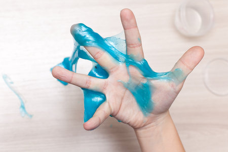 Blue slime stretchable toy for children in hands. An elastic antistress toy for relaxation. Gum for hands. Funny Games. Slime isolated. Copy space, place for textの写真素材