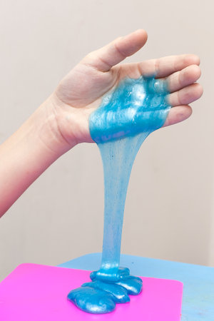 Modern toy called slime. Child playing transparent blue slime. Hands holding a mucus isolated on a white background. Selective focusの写真素材