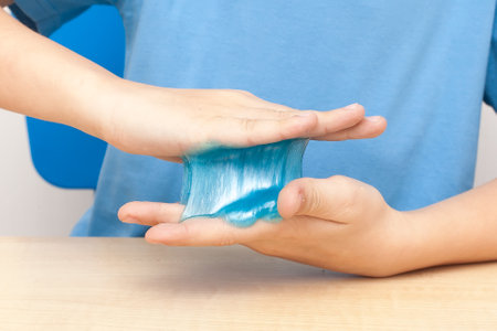 Blue slime stretchable toy for children in hands. An elastic antistress toy for relaxation. Gum for hands. Funny Games. Slime isolated. Copy space, place for textの写真素材