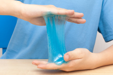 Modern toy called slime. Child playing transparent blue slime. Hands holding a mucus isolated on a white background. Selective focusの写真素材