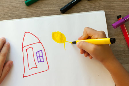 Child draws a pencil drawing of the peace. Green field, the bushes and the houseの写真素材