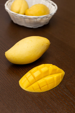 Mango. Close up of fresh ripe mango fruit with leaves over dark wooden table background with green...
