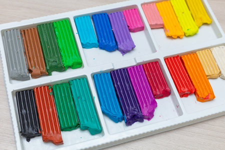 Air plasticine mass for modeling painted with bright colors, ultralight plasticine, all colors rainbow spread out on yellow background. Childrens hands sculpt ball plasticine. School creative taskの写真素材