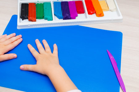 Air plasticine mass for modeling painted with bright colors, ultralight plasticine, all colors rainbow spread out on yellow background. Childrens hands sculpt ball plasticine. School creative taskの写真素材