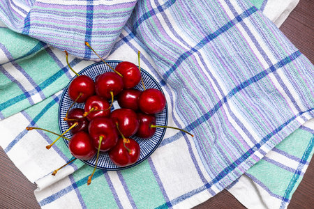 Bowl and board with sweet cherries on black background.の写真素材