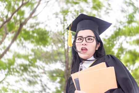 Young crazy asian woman graduating holding diploma with pride and funny in an academic...
