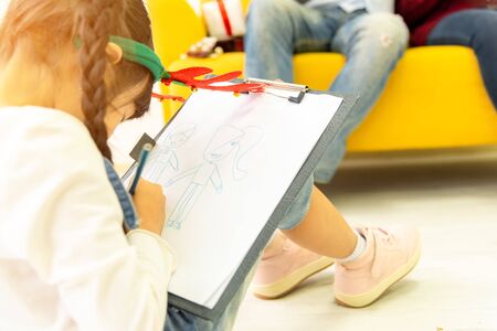 Happiness family leisure time in living room togetherness .Asian family having good time at home sitting on floor and sofa, playing ,drawing , little girl having fun. Friendship relax time concept.の写真素材