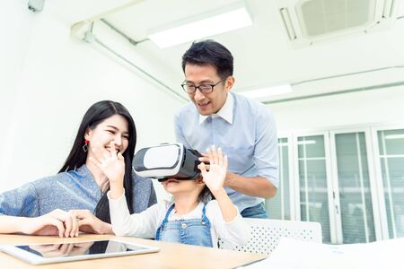 Happiness family leisure time in living room togetherness .Asian family having good time at home sitting on desk, playing ,drawing gadget technology media, little girl having fun. relax time concept.の写真素材