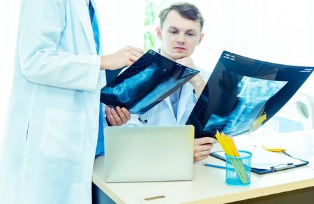 Experience male and female doctors orthopedics and team expert discussing x-ray film, surgery with...