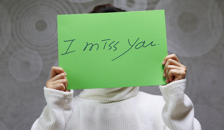 Woman wearing a white sweater. handwritten letter I miss you