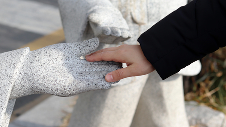 Hands touching the stone statue's handsの写真素材