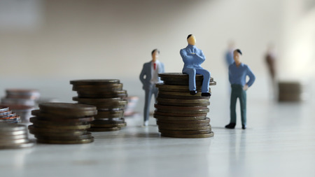 concept of working people. The man is sitting on the coin and standing behind it.