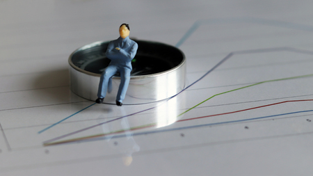 The miniature man sitting on the compass.の写真素材