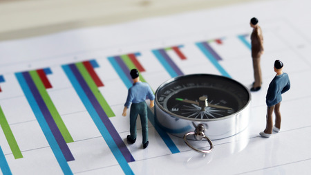 Appearance from behind compass and three miniature man on the chart.の写真素材
